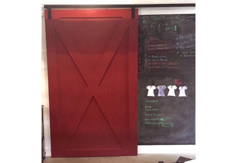 Bright red barn door with black track next to chalkboard 